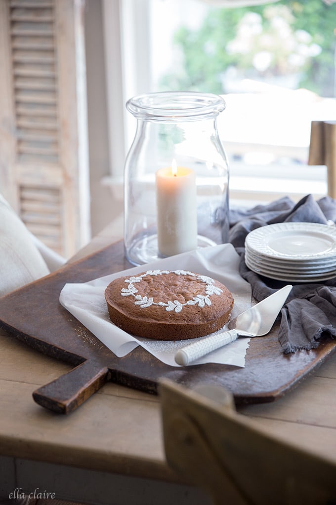 DIY fall stenciled wreath pumpkin cake with candlelight, antique bread board, and vintage linen towel.
