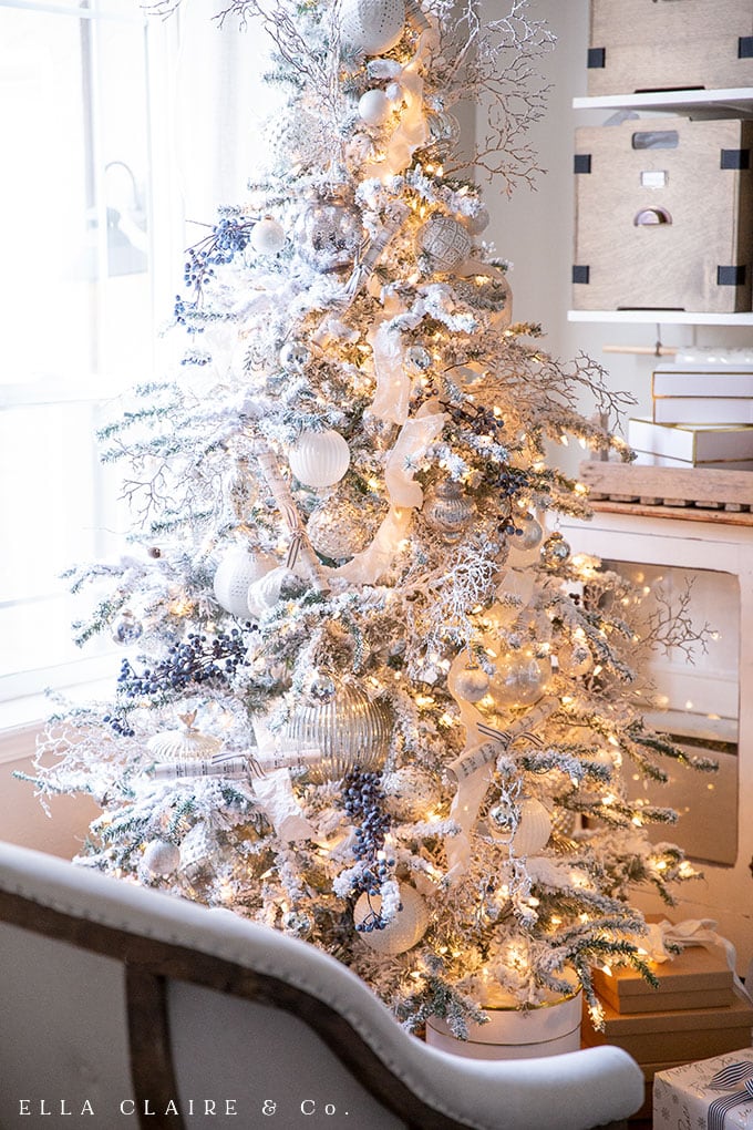 This flocked Christmas tree is effortlessly elegant, decorated in shades of white, clear, silver and a little bit of blue. In keeping with the traditional Christmas colors theme, little pops of red were added to the room with gift wrapping and ribbon.