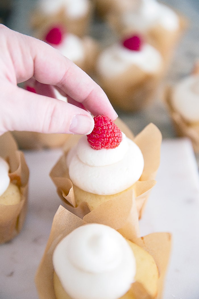 Vanilla buttercream cupcakes with a raspberry on top for a delicious and understated Valentine's Day treat.