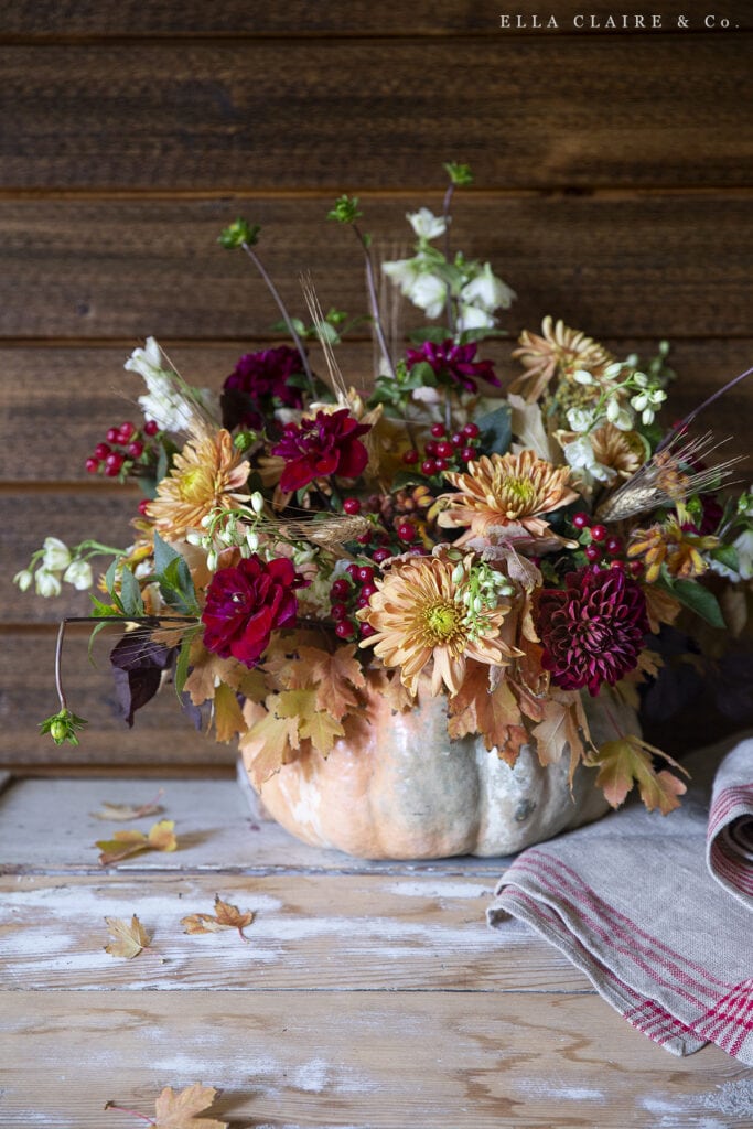 rustic warm fall flower centerpiece in a pumpkin