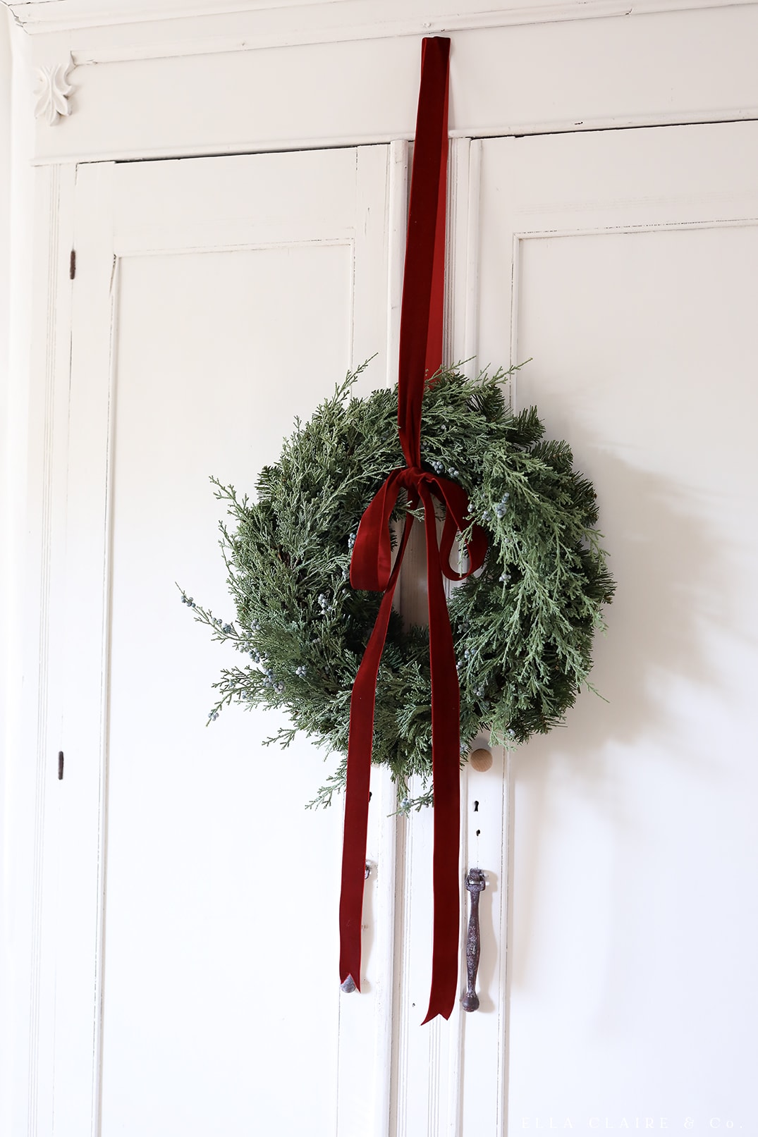 green wreath hanging from red velvet ribbon
