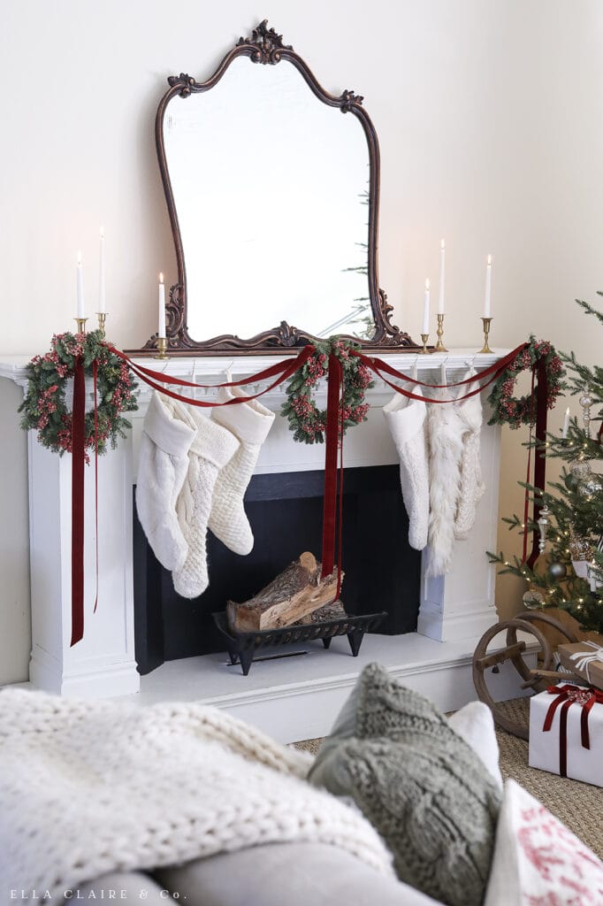 Christmas mantel with green wreaths and red velvet ribbon